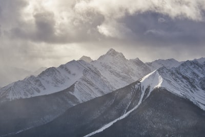 白天多云的天空下被雪覆盖的山